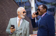 © liderina - Two business men talking on the street. Using smart phones.