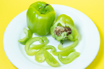 Sliced green peppers in a plate on a yellow background. Healthy diet food made from fresh vegetables. Vegetarian food