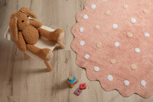 Round Pink Rug With Polka Dot Pattern And Toys On Wooden Floor In Baby's Room, Above View