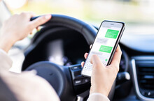 Driving Car And Using Phone. Distracted Driver Texting With Mobile Cellphone. Irresponsible Woman Checking Sms Message With Smartphone In Traffic. Auto Accident Concept. Holding Smart Device In Hand.