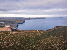Aerial View Of A Lone Boat Along The Wild Coastal In Sagres At Sunset, Sagres, Algarve Region, Portugal.