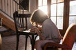 © Mint Images - young boy writing on small chair at sunset
