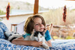 © Mint Images - Young boy lying on outdoor bed stroking a pet cat
