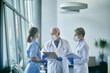 © Drazen - Senior doctor and his medical team wearing face masks while communicating in hallway at the hospital.