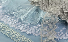 Pile Of Blue, White, Gray Gentle Guipure, Lace Fabric On Blue Background. Use For Atelier