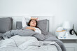 © Freedomz - Asian woman feeling sick and sleeping in blanket on the bed while holding tissue in hand and touching forehead