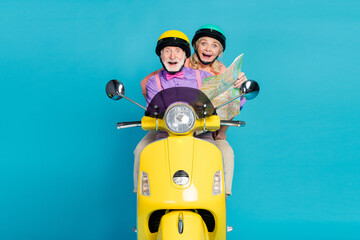 Poster - Photo of grey haired married couple ride bike happy hold map vacation trip isolated on pastel blue color background