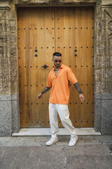 Poster - Vertical shot of a handsome male in casual clothes posing by an old building in Spain