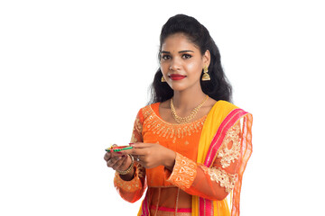 Portrait of a Indian Traditional Girl holding Diya, Girl Celebrating Diwali or Deepavali with holding oil lamp during festival of light on white background