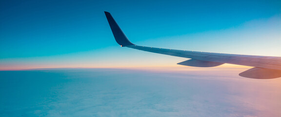 Top view from inside window airplane of a sunset sky and wing