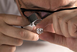 Fototapeta  - Close up of diamond dealer's hands evaluating diamond at international jewelry exhibition. High quality photo