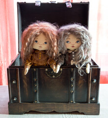 Two textile dolls in an open wooden chest. Childhood.