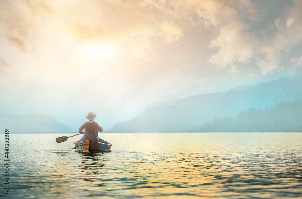 Back view of lonely fisherman in boat on morning lake - obrazy, fototapety, plakaty 