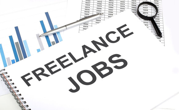 In the notebook, the text FREELANCE JOB , next to magnifier and a pen, the background is graphics.