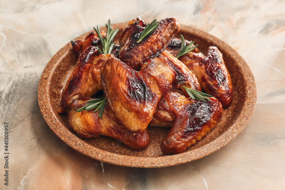 Plate with roasted chicken wings on grunge background