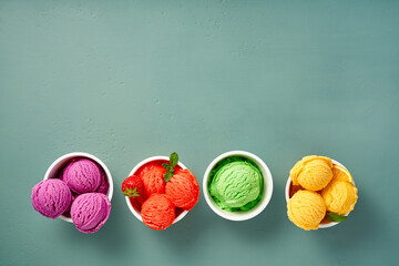 Wall Mural - Gourmet flavours of Italian ice cream in vibrant colors served in individual ice cream paper cups on blue background. Strawberry sorbet, blueberry or lavender ice cream with orange sorbet and kiwi ice