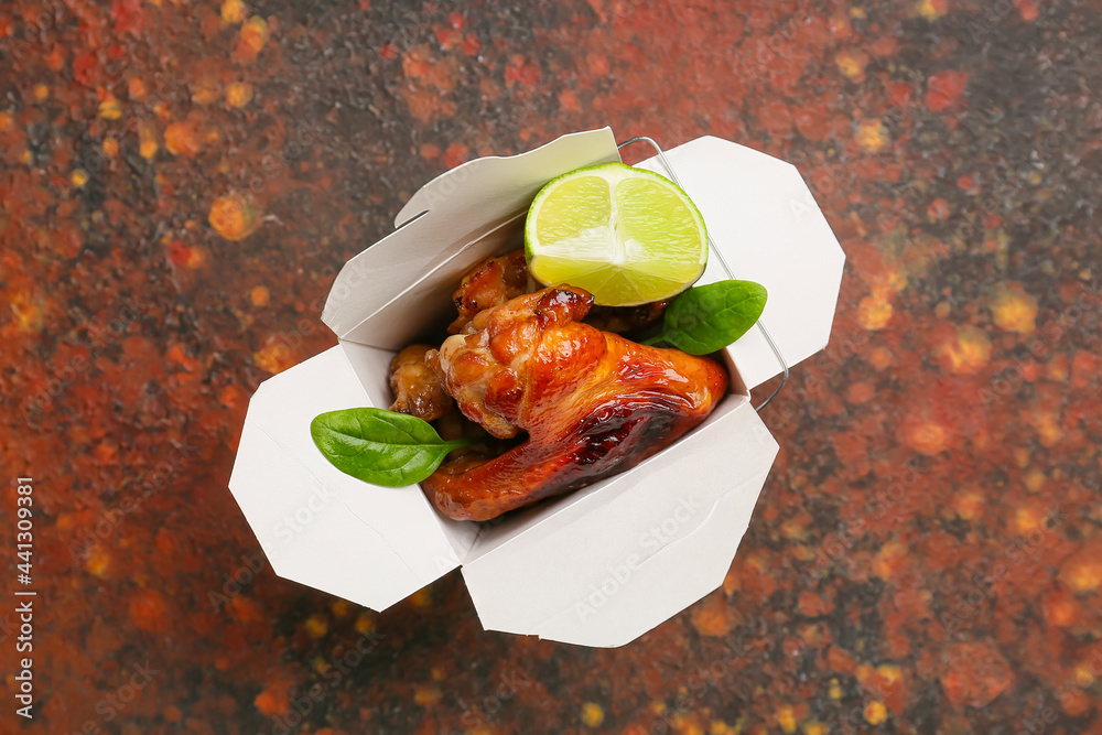 Box with roasted chicken wings on grunge background
