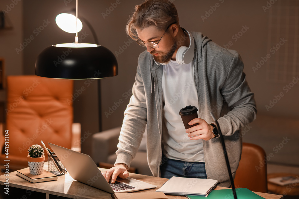 Young man studying online at home in evening