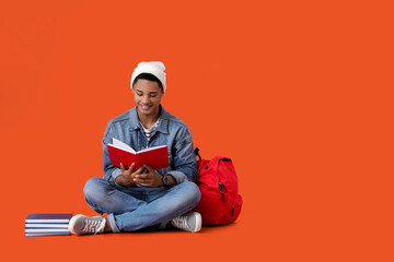 Canvas Print - Male African-American student with book on color background