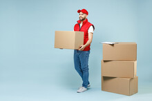 Full Size Body Length Delivery Guy Employee Man In Red Cap White T-shirt Vest Uniform Work As Dealer Courier Hold Blank Cardboard Box Isolated On Pastel Blue Color Background Studio. Service Concept.