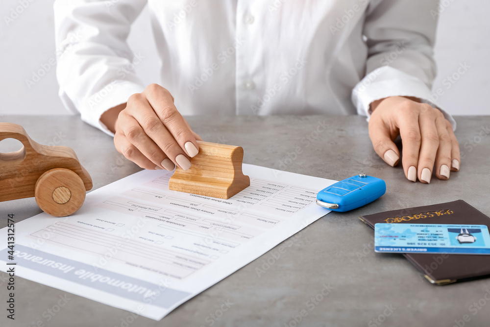 Woman with stamp and automobile insurance in office