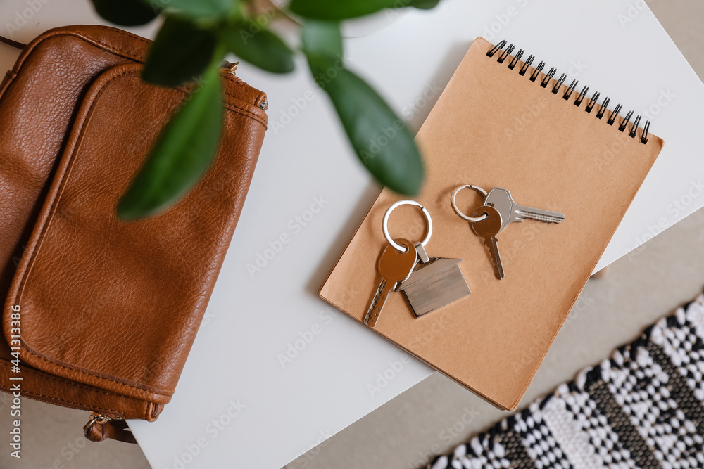 Keys with notebook and bag on table in room