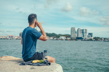 Wall Mural - The young athlete was listening to music and looked at the city during his break after exercise. Music and sport concept.