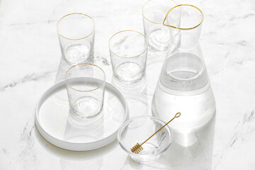 Beautiful empty glasses, jug and plate on light background