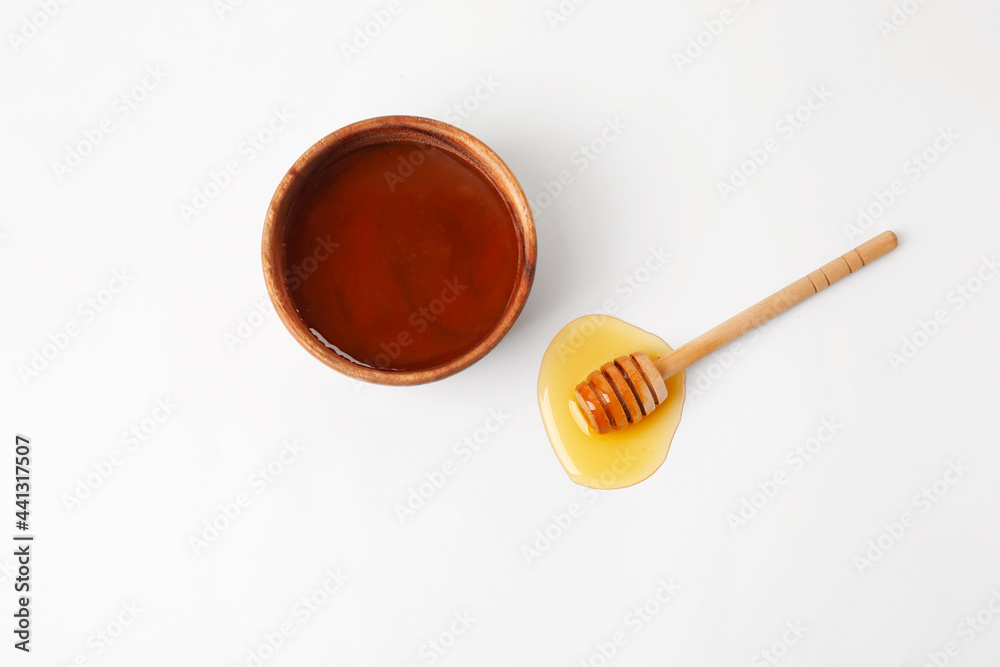 Bowl with sweet honey and dipper on white background