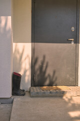 summer sun day near a suburban white house in the sun near the door there are two pairs of black rubber boots shadows