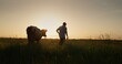 The owner leads his cow through the meadow at sunset. Small farmers concept
