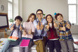 © Studio Romantic - Happy teacher and elementary school student children holding thumbs up gesture looking at camera. Smiling educator and cheerful study kids group voting positive, giving agreement. Back to school