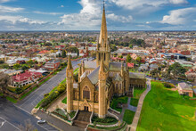 Aerial View Of A Cathedral On A Grassy Hillside In A Regional City