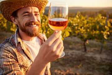 Happy winemaker with glass of wine in vineyard