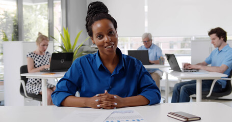 Happy african businesswoman sitting at desk and smiling having video call.