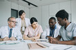 © Seventyfour - Large group of doctors working together at meeting table during medical conference