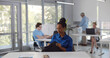 © nimito - Young afro-american woman sitting at desk and opening bag in office