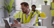 © TommyStockProject - Portrait of male engineer in reflective vest eating lunch and working on laptop in office