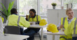 © TommyStockProject - Multiethnic workers in safety uniform eating meal in factory canteen