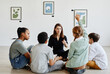 © Seventyfour - Full length view at diverse group of children sitting in circle during class in art gallery with female teacher