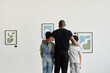 © Seventyfour - Minimal back view at African-American family looking at paintings in modern art gallery, copy space