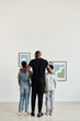 © Seventyfour - Full length back view at African-American family looking at paintings in modern art gallery, copy space