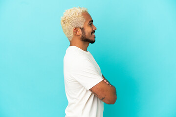 Wall Mural - Young Colombian handsome man isolated on blue background in lateral position