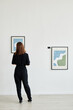 Minimal back view portrait of young woman looking at paintings in modern art gallery, copy space