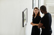 © Seventyfour - Side view portrait of elegant couple looking at abstract paintings in modern art gallery, copy space