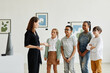 © Seventyfour - Diverse group of children listening to female expert while visiting modern art gallery, copy space