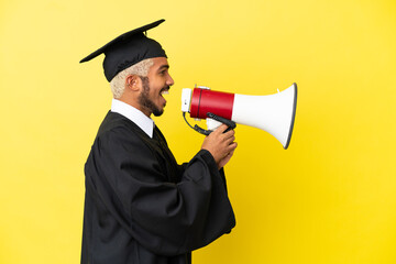 Wall Mural - Young university graduate Colombian man isolated on yellow background shouting through a megaphone