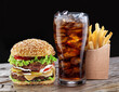 Delicious hamburger with cola and potato fries isolated on wooden table and on black background. Fast food concept.