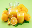 Yellow orange fruits and fresh orange juice isolated on light green background.