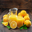 Yellow orange fruits and fresh orange juice isolated on dark wooden background.